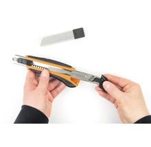 Mains tenant un cutter avec lames de rechange
