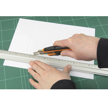 Découpe de papier à l''aide d''un cutter et d''une règle sur un tapis de découpe
