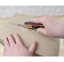 Une personne ouvre un carton avec un cutter.