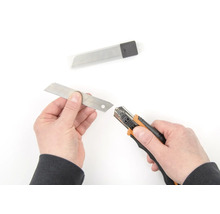 Mains changeant la lame d''un cutter