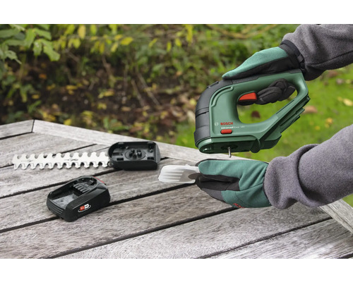 Cisailles à gazon sans fil avec accessoires sur une table en bois