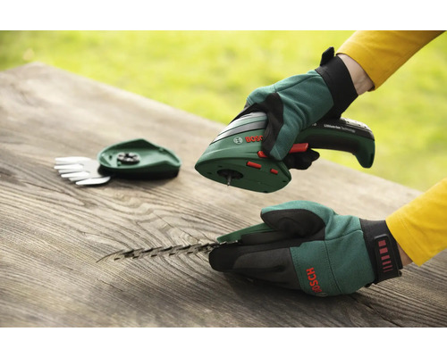 Akkuschere mit Gras- und Strauchmesseraufsatz der Marke Bosch auf einem Holztisch