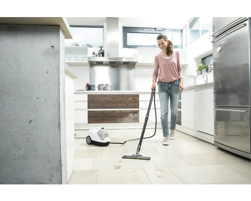 Femme nettoie carrelage dans cuisine avec nettoyeur vapeur