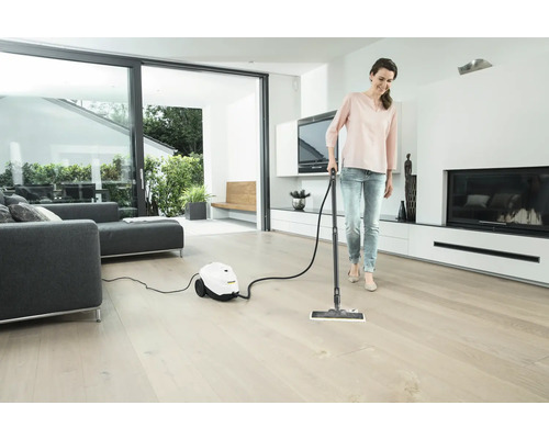 Femme nettoie le parquet avec un nettoyeur vapeur dans un salon lumineux