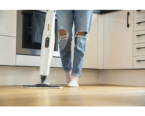 Une personne utilise un nettoyeur vapeur Kärcher sur un plancher en bois dans une cuisine.