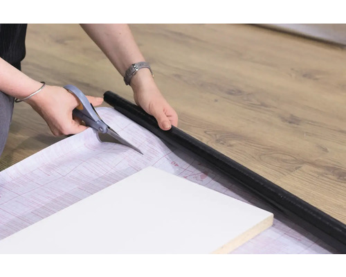 Person schneidet mit einer Schere eine Folie zu, um ein Möbelstück zu bekleben