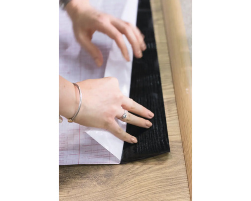 Selbstklebende Bodenfliese wird verlegt.