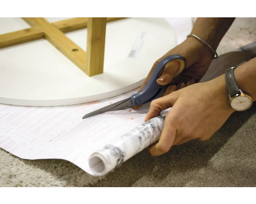 Découpe de film autocollant pour meubles avec des ciseaux pour une table
