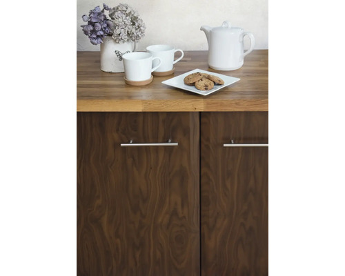 Küchenszene mit Geschirr, Gebäck und Blumendekoration auf einer Arbeitsplatte über einem Schrank