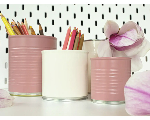 Arrangement von lackierten Dosen als Stiftehalter mit Buntstiften und Magnolienblüten