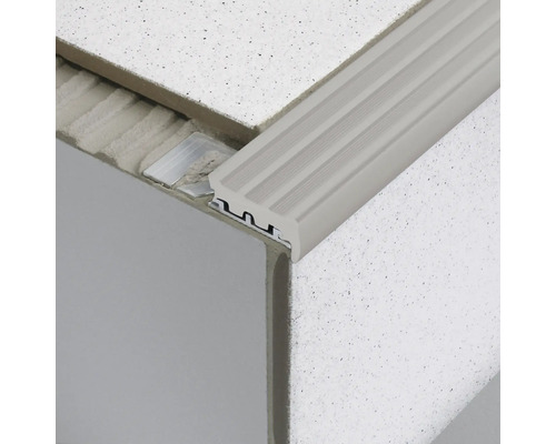 Gros plan sur un profilé de bordure d''escalier en aluminium, monté sur une marche d''escalier carrelée.
