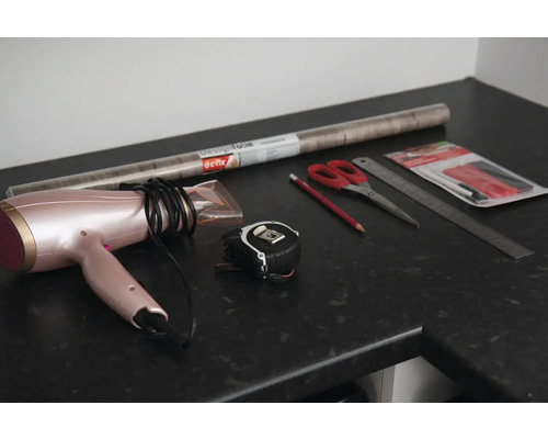 Film décoratif, sèche-cheveux, mètre ruban, ciseaux, crayon, règle et outils pour appliquer le film sur un plan de travail