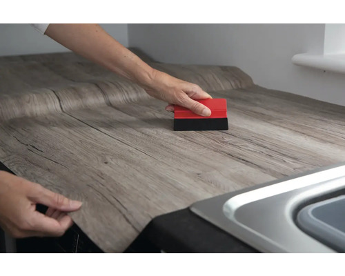 Application d''un film décoratif en bois sur un plan de travail avec une raclette