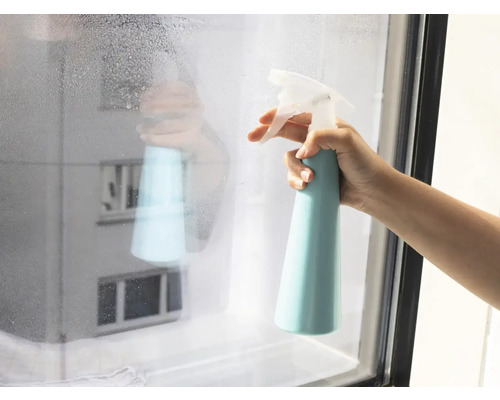 Hand sprüht Fenster mit Reinigungsmittel