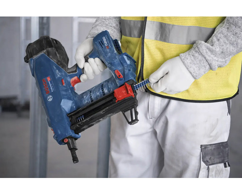 Eine Person befüllt einen blauen Bolzensetzer der Marke Bosch mit Bolzen.