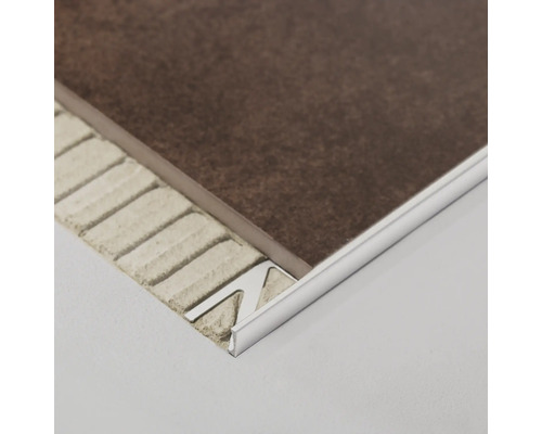 Detailaufnahme einer Fliesenleiste aus Metall zwischen einer Fliese und dem Untergrund