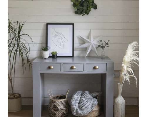Intérieur décoratif avec console, art, plantes et paniers dans une pièce lumineuse.