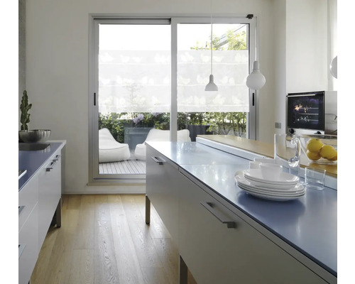 Cuisine claire avec îlot de cuisine, vaisselle et vue sur la terrasse avec poufs