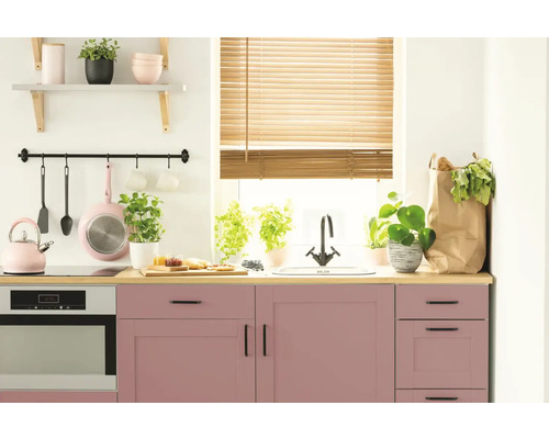 Helle Küche mit rosa Schränken, Holzjalousien und verschiedenen Küchenutensilien.