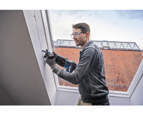 Un homme utilise une scie sabre sur un mur
