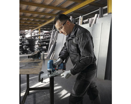 Un homme coupe une tôle avec une scie sauteuse sans fil