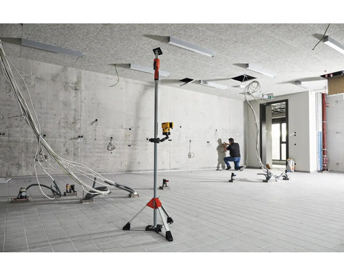 Baustelle mit Kreuzlinienlaser auf Stativ und Elektriker bei der Arbeit