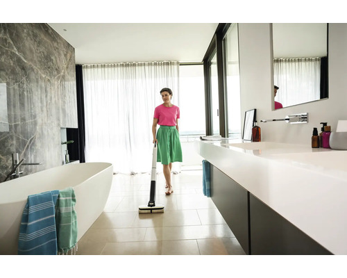 Une femme nettoie une salle de bains avec une serpillère électrique.