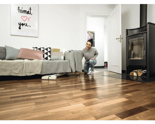 Salon avec parquet, canapé, cheminée et une femme utilisant une serpillère électrique sans fil