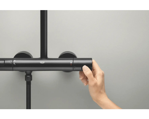 Grohe Logo auf einer Duscharmatur, an der eine Hand die Temperatur einstellt