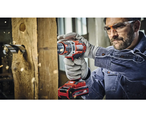 Ein Mann bohrt mit einem Akku-Bohrschrauber ein Loch in ein Holzbrett.