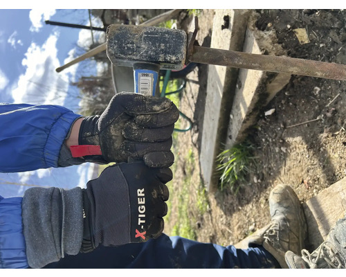 Personne gantée frappant un morceau de métal avec un marteau