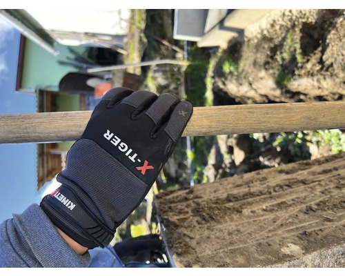 Une main gantée tient un manche de bêche pendant le creusement.