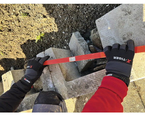 Personne portant des gants nivelant des blocs de béton avec un niveau à bulle