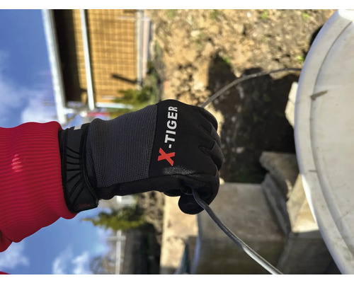Une main gantée X-Tiger tenant un câble.