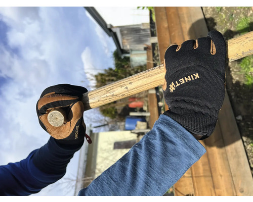 Eine Person mit Arbeitshandschuhen hält einen Hammer.