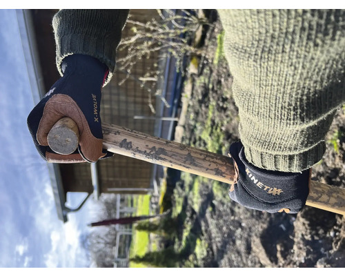 Hände mit Arbeitshandschuhen halten einen Holzstiel