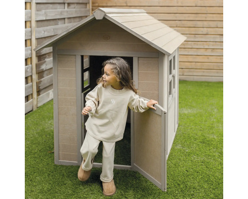 Un enfant sort d''une cabane en bois dans le jardin.