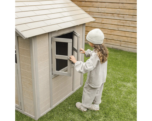 Une fille ouvre la fenêtre d''une cabane en plastique dans le jardin.