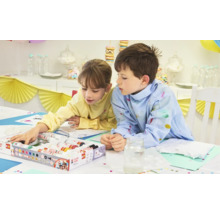 Deux enfants peignent des t-shirts avec de la peinture textile sur une table.