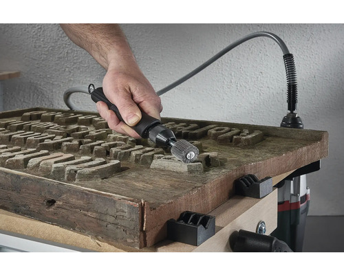Main travaillant une surface en bois avec un outil abrasif