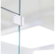 Weisser Fenster- oder Türkontaktsensor an einer Glasscheibe befestigt