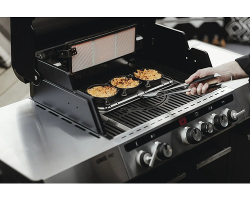 Un barbecue avec de la nourriture est utilisé avec une pince à barbecue.