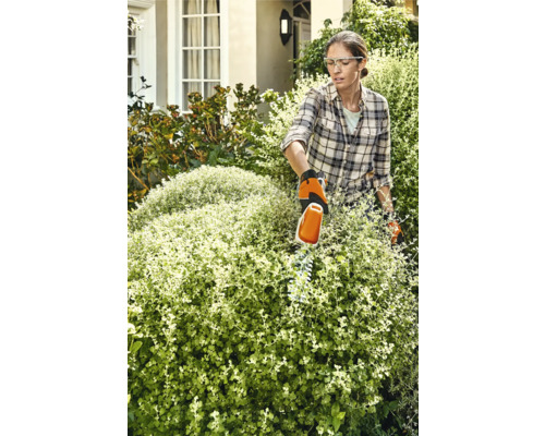 Frau schneidet Hecke mit Heckenschere im Garten