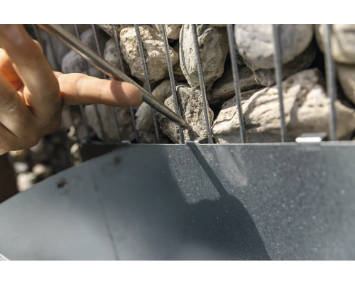 Gros plan d''une gabion remplie de pierres, en cours de traitement avec un outil.