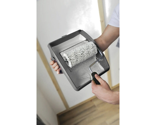 Person hält eine Farbwanne mit Farbroller in der Hand.