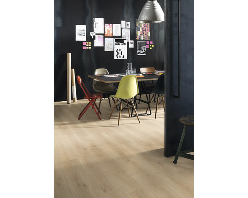 Une salle à manger avec parquet, une table et diverses chaises devant un mur sombre avec des notes.