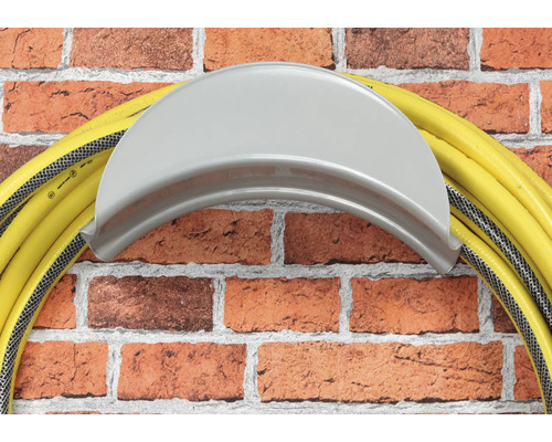 Tuyau d''arrosage jaune sur support de tuyau sur un mur en briques