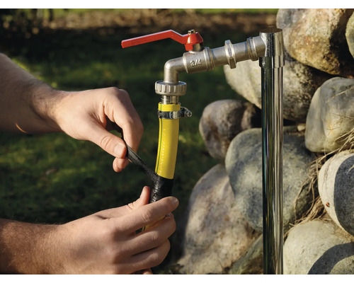 Person repariert einen Gartenschlauch mit Isolierband an einem Wasserhahn.