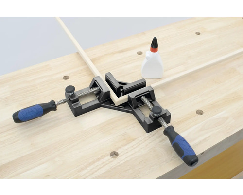 Un serre-joint d''angle maintient deux morceaux de bois à un angle de 90 degrés sur un établi.