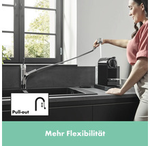 Küchenszene mit Spültischarmatur mit Ausziehfunktion und einer Frau, die eine Kaffeemaschine befüllt